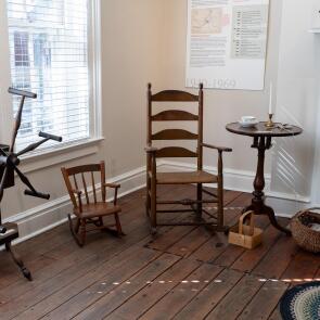 Historic wooden chairs and spinning wheel in a period room.